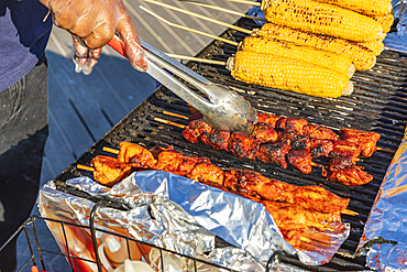 Coney Island, Brooklyn, New York City, New York, USA. Meat kebabs and corn on the cob at a sidewalk food stand.