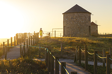 A tourist observes sunset at Windmills of Apulia during summer, Apulia, Esposende, Braga, Norte, Portugal, Europe