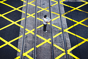 A tourist reads the newspaper on the pedestrian crossing, Central District, Hong Kong, China, Asia