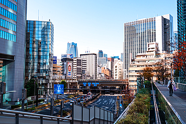 A vibrant view of Tokyo’s skyline featuring train tracks weaving through modern skyscrapers in a busy district.