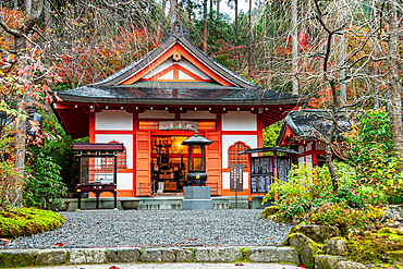 A vibrant red shrine surrounded by greenery and autumn colors, located near Sanzen-in Temple in Ohara, Kyoto, Japan.