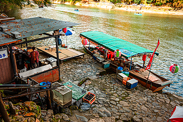 Traditinal Docked rowboats along Katsura River in Kyoto, with vibrant autumn colors and tranquil waters creating a serene atmosphere.