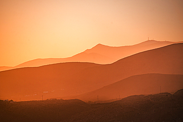 Golden hues blanket the rolling mountains of Almería, Spain, as the setting sun creates a dreamy, layered silhouette effect