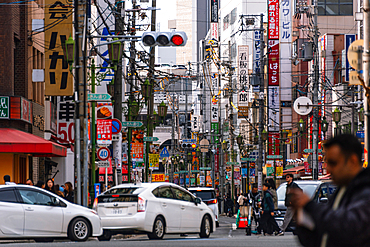 A busy street full of neon lights and advertisement signs filled with colorful signs, power lines, pedestrians, and vibrant city life in Osaka, Kansai, Japan. Nipponbashi Denden Town