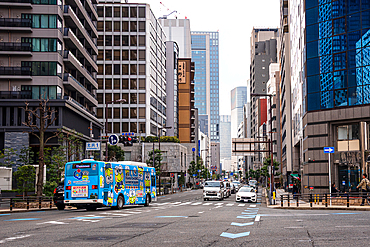 Streets of Osaka, Japan. a blue bus amidst skyscraper in the Nakanoshima area.