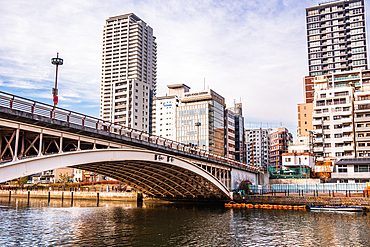 Bridge leading over the River at Nakanoshima Park in central Osaka. Skyscrapers reflecting in the waters on the other riverbank. Japan