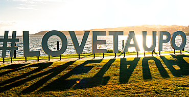 Love Taupo sign on the shore of lake Taupo in sunset light. A scenic point of North Island of New Zealand