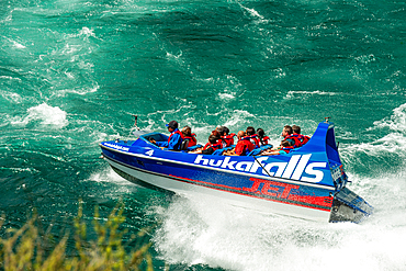 Tourists in a jet boat on the wild white waters of Huka falls on the Waikato River, Taupo, North Island, New Zealand