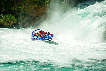 Tourists in a jet boat on the wild white waters of Huka falls on the Waikato River, Taupo, North Island, New Zealand