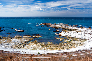Blue Ocean and Exposed Rocky Reefs Under Bright Sky at Kaikoura Peninsula, New Zealand. Point Kean Viewpoint