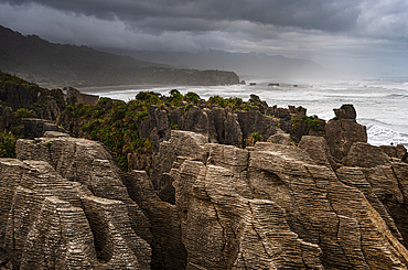 Layered Limestone Columns of Pancake Rocks With Misty Coastline in the Background, Paparoa National Park, New Zealand