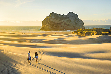 Couple Walking Along Giant Sand Dunes at Wharariki Beach with Archway Islands in Background, Golden Bay, New Zealand