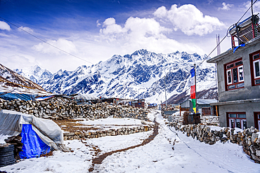 Snowy Path Through Stone Walls and Lodges in Kyanjin Gompa Village Peaks in Background, Nepal lookign towards Langshisha Ri and the Langtang glacier.