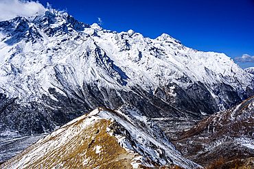 Aerial view of ridgeline leading toward rugged snow-covered mountains above Langtang Valley near Kyanjin Gompa, Nepal. Summit of Lower Kyanjn Ri