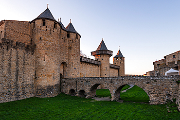 Evening light on the medieval towers and arched stone bridge of Château Comtal in the fortified Cité de Carcassonne, Aude, France