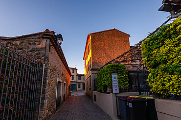 Early evening light along a narrow lane between stone houses in La Bastide Saint-Louis, Carcassonne