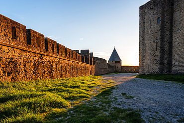 Warm Sunset Light Reflecting Off Ancient Fortified Walls of Carcassonne with Mossy Stonework and Tower Silhouettes