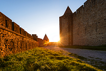 Golden Sunburst Framed by the Towering Stone Fortifications of Carcassonne at Dusk Along a Medieval Path