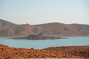 Still waters of Barrage Al-Hassan Addakhil in Parc National Al Hassan Addakhil near Errachidia, surrounded by arid red hills and rugged mountain slopes