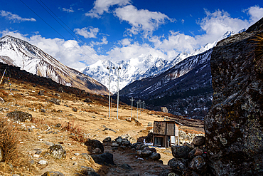 Small shelter and prayer flags along mountain path with stunning view of snow-covered Gangchempo, Langtang Himalay, Nepal