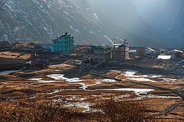 Evening light over Langtang Village with reflections in terraced fields and colorful buildings nestled between steep Himalayan walls in Langtang Valley. ' Skyline' of Lantang Village