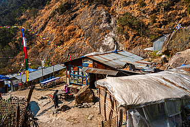Remote mountain teahouse village with prayer flags and hikers near the Langtang Valley trail in Nepal