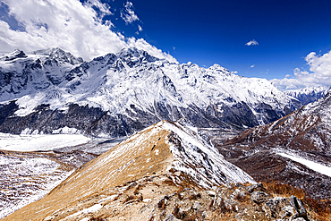 Narrow snow-covered ridge trail ascending toward Kyanjin Ri with panoramic views of Langtang Himal and Scout Peak, Langtang National Park, Nepal