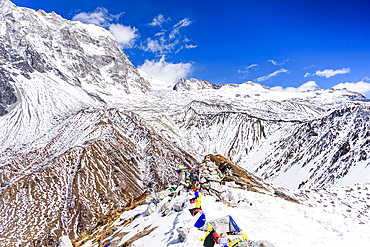 High-altitude view north from Kyanjin Ri summit with prayer flags and dramatic snow-covered ridges above Ubra and Kimshung, Nepal