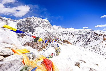 Colorful prayer flags draped along the snow-covered summit of Kyanjin Ri with Langtang lirung slopes in the background, Langtang Valley