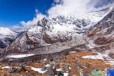 Dramatic view of Langtang Lirung glacier beneath towering Himalayan peaks and prayer flags from Kyanjin Ri, Langtang Valley
