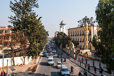 Busy street scene in central Kathmandu with traffic, motorbikes, pedestrians, and the historic Ghanta Ghar clock tower