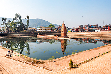 Stone steps surrounding the Siddha Pokhari pond in Bhaktapur, reflecting temple structures and distant hills