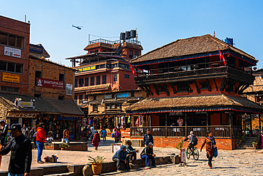 Tourists and locals walking in front of the intricately carved wooden temples of Bhaktapur’s Taumadhi Square