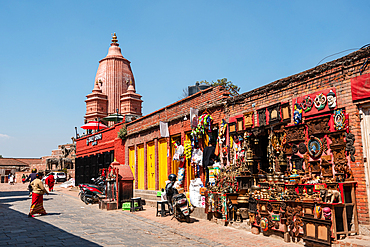 Souvenir and handicraft stalls lining a sunny street near the red Nyatapola Temple in Bhaktapur, Nepal