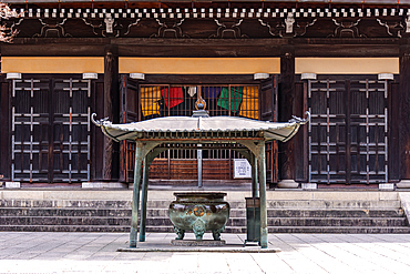 Front view of Chion-in Temple’s main hall in Kyoto, featuring dark wooden architecture, a traditional incense burner, and multicolored Buddhist banners