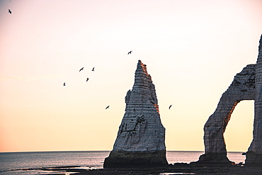 fly past the famous NeedleAiguille d'Etretat and Arch rock Falaise d‘Aval formations at a Golden sunrise in Étretat, Normandy, France.