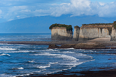Rugged sea cliffs rise above the crashing waves on the wild West Coast Cape Foulwind of New Zealand’s South Island.