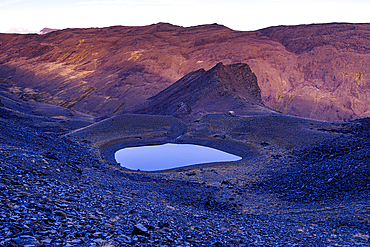 Glacial lake Piedra de los Capuzones glows at dusk among rugged peaks in the Sierra Nevada, Andalusia, Spain.