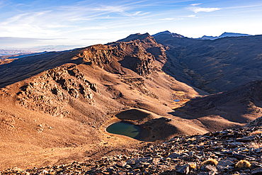 A high-altitude lake lies beneath rocky ridges near Pico del Caballo in the Sierra Nevada, Andalusia, Spain.