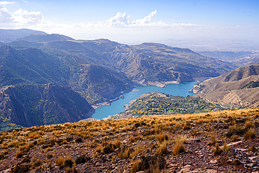 A turquoise mountain lake of Guejar Sierra sits below steep ridges in the Sierra Nevada, Andalusia, Spain.