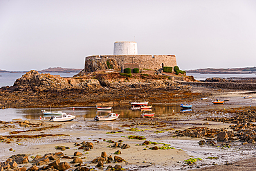 Small fishing boats resting on tidal sands near Fort Grey in Rocquaine Bay, Guernsey, Channel Islands, United Kingdom.