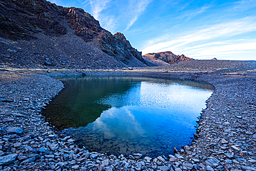 Clear mountain reflections in a high alpine tarn near Cerro del Caballo in Sierra Nevada National Park, Andalusia, Spain.