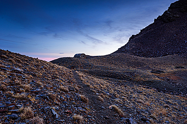 Rolling high mountain ridges fading into dusk light around Cerro del Caballo. Following the path towards a mountain refuge in Sierra Nevada National Park, Andalusia, Spain.