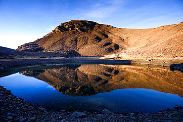 Reflections in laguna del caballo, one of the remote glacial lakes below Cerro del Caballo in Sierra Nevada National Park, Andalusia, Spain.