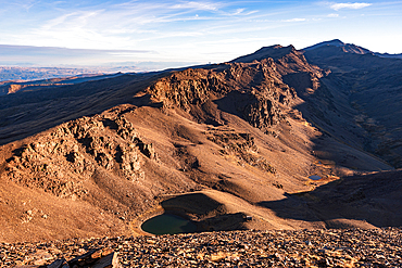 High alpine tarn in the glacial cirque beneath Cerro del Caballo in the Sierra Nevada in the light of sunrise National Park, Andalusia, Spain.