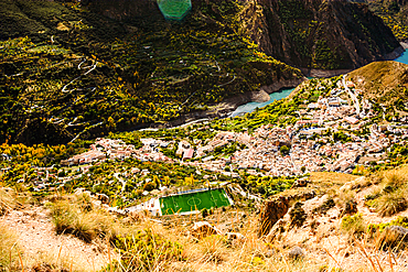 Aerial view of the white washed village of guejar sierra on the foot of the Sierra Nevada next to the blue guerja Embalse lake.