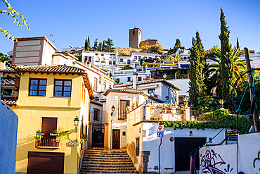 Narrow street in the Albaicín quarter leading uphill toward the San Cristobal Church tower, UNESCO World Heritage Site, Granada, Spain.