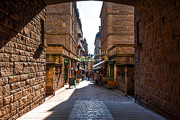 Quiet cobbled alleyway with stone houses inside the fortified walls of Saint-Malo, Brittany, France, illuminated by afternoon light