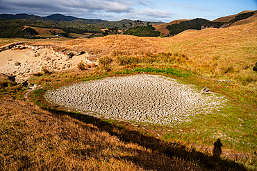 Arid farmland in New Zealand’s South Island with dried pond and golden grass hills under summer drought conditions.
