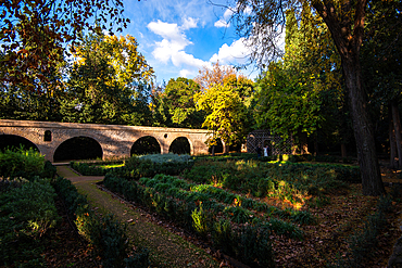 Historic stone bridge in shaded gardens of Carmen de los Mártires Granada Andalusia Spain